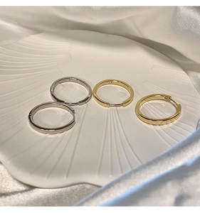 Close-up of minimalist gold and silver hoop earrings on a decorative shell tray