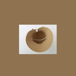 Detail of straw sun hat interior showing sweatband, elastic chin strap and care label