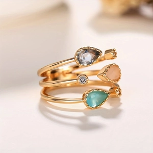 Macro detail of triple-layer gold ring with pear-cut crystal stones and cubic zirconia