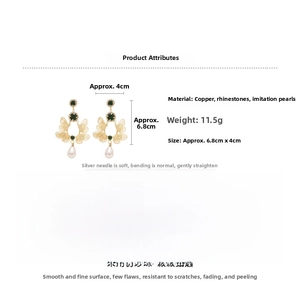 Detail view of gold butterfly drop earrings with green rhinestones and pearl pendant