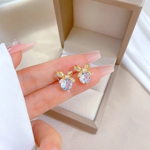 Elegant gold bow earrings with large round zircon and micro-pave crystals held by hand