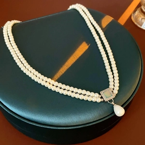 Macro detail of French vintage pearl necklace with square pendant and drop pearl on jewelry box