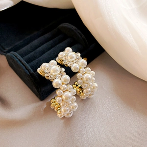 Macro shot of gold C-shaped earrings with faux pearls and rhinestones on black velvet