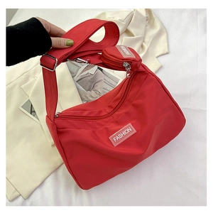 Detail view of red nylon shoulder bag with wide strap and matching round coin purse