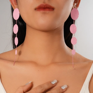 Macro view of pink long drop earrings with geometric circular texture on female model