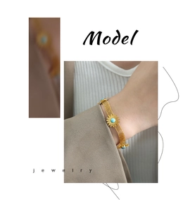 Detail of woven mesh gold bracelet featuring a turquoise sunflower charm on model's wrist