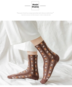 Detailed knit texture of brown mid-calf socks with orange floral patterns on model