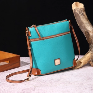 Detail of turquoise pebbled leather crossbody bag with brown trim and gold hardware