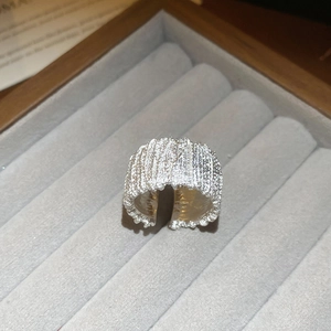 Macro shot of silver textured crinkle ring with adjustable open band on gray velvet