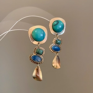 Macro detail of French vintage hollow teardrop earrings with colorful inlaid gemstones