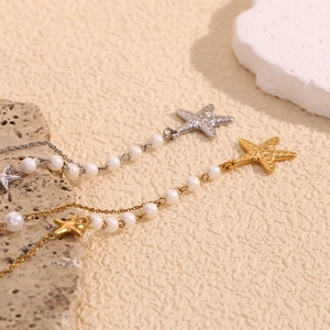 Detailed macro view of gold and silver starfish pearl necklaces on beige stone