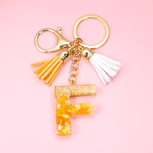 Detail of resin letter F keychain with gold foil flakes and double silk tassels
