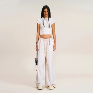 Detail view of cream wide-leg trousers with adjustable drawstring and cross logo detail