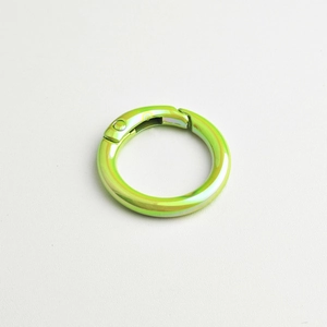 Close-up of circular metallic spring ring clasp in gradient iridescent green finish