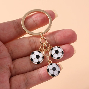 Detail of a gold-tone keychain with three black and white mini soccer ball charms