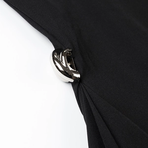 Detail of a silver metallic buckle on black high-neck dress with fine fabric texture