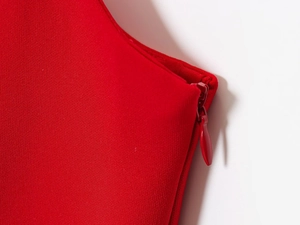 Detailed close-up of a concealed side zipper on a red pleated hem sleeveless top