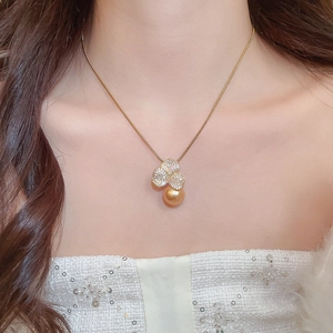 Detailed close-up of a golden pearl necklace with a sparkling floral diamond pendant on neck