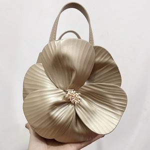 Detailed shot of a champagne gold petal-shaped handbag with metallic leather finish