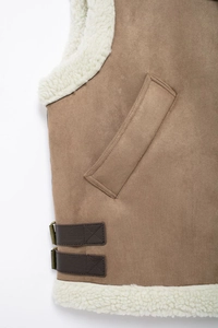Detail of brown faux suede vest with plush white faux fur lining and side buckle straps