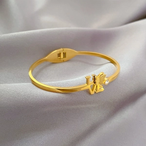 Detailed view of golden butterfly bangle with LOVE engraving and sparkling single crystal