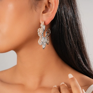 Macro shot of silver hollow leaf earrings on model showing artistic metallic texture