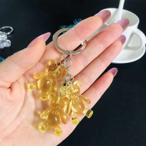 Handheld view of three translucent yellow resin gummy bear charms on a metal keychain
