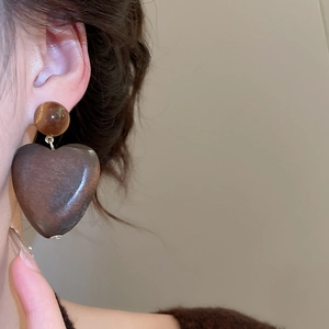 Gros plan de boucles d'oreilles cœur en bois rétro avec perles d'ambre sur un modèle