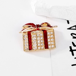 Christmas gift box brooch with crystals and red enamel on a decorative stone base