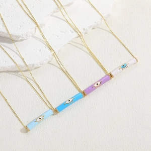 Detail showing colorful enamel cylindrical evil eye pendants with gold chains on stone