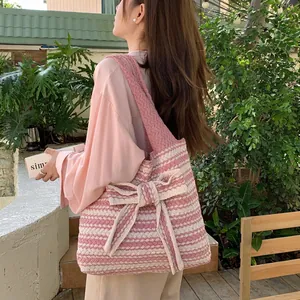 Pink and white striped knit tote bag with a large bow shown on a female model