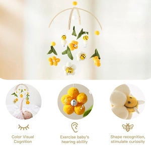 Detail of wooden baby mobile with yellow bees and felt flowers for hearing stimulation