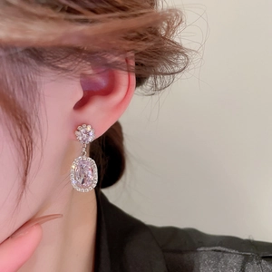 Close-up of elegant silver flower pearl earrings with zircon inlay worn by a model