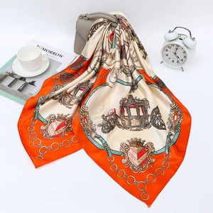 Detail of satin scarf featuring orange horse carriage and chain print styled with a handbag