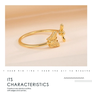 Detailed close-up of adjustable gold-plated butterfly open ring on warm beige texture