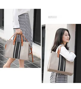 Detail showing striped canvas tote bag with brown leather handles and a long shoulder strap