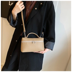 Detail of beige litchi grain leather handbag with silver zipper and top handle strap