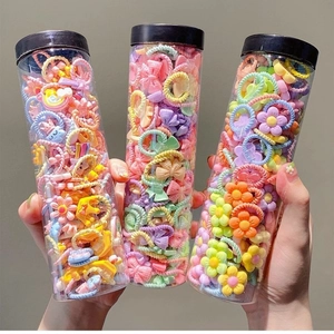 Set of three cylinders with colorful elastic hair ties featuring flower and bow charms