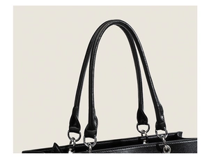 Close-up of black PU leather handles and metallic ring connectors for the Ita shoulder bag