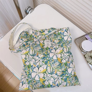 Dettaglio ravvicinato di una borsa tote in tela floreale con fiori blu e foglie verdi fresche
