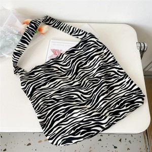 Flat lay of a zebra print canvas tote bag with a wide strap on a clean white background