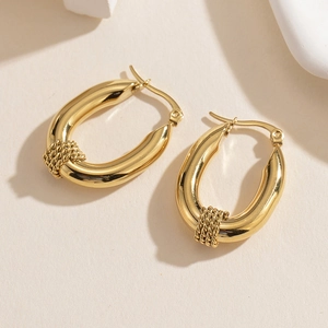 Detailed macro view of gold-plated chunky oval hoop earrings with woven metal texture