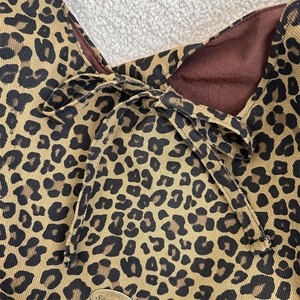 Close-up of leopard print canvas tote with fabric bow and gold metal logo plaque