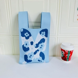 Macro detail of butterfly knit tote bag fabric texture with blue and white floral pattern