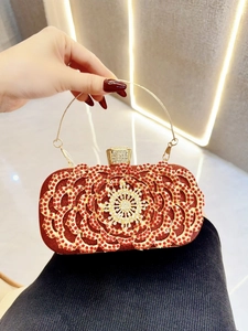Close-up of luxury red evening clutch with gold filigree and rhinestone detailing
