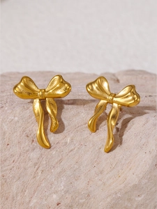 Vue détaillée de boucles d'oreilles nœuds dorées élégantes sur une surface en pierre