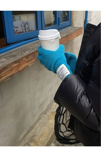 Close-up of blue wool knit gloves with vintage textile label detail on the wrist