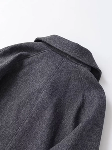 Detailed close-up of charcoal grey wool texture and lapel stitching on the short coat