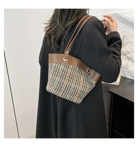 Detailed side view of the houndstooth patchwork tote bag with brown leather straps
