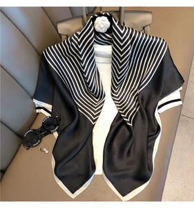 Detail of silk scarf with black and white stripes draped elegantly on a leather chair